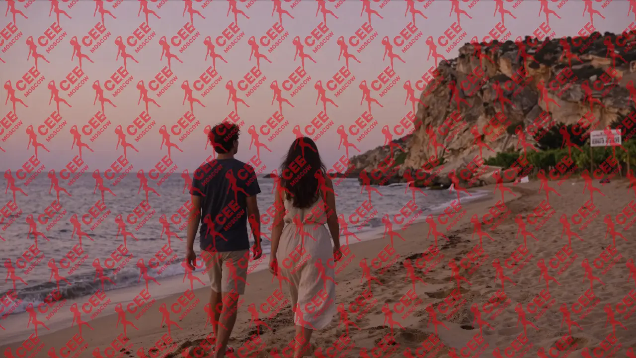 Женщина и мужчина гуляют по скрытому пляжу на Кипре на закате, без признаков коммерции.